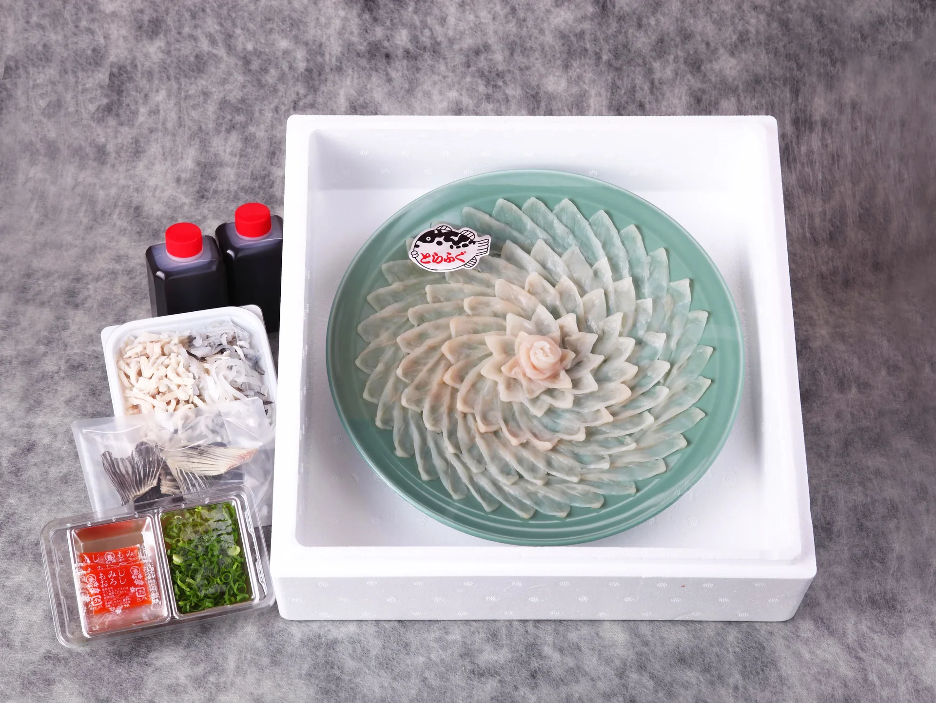 発泡スチロールに梱包された、職人技が光る鮮やかなふぐの薄造りとタレのセット